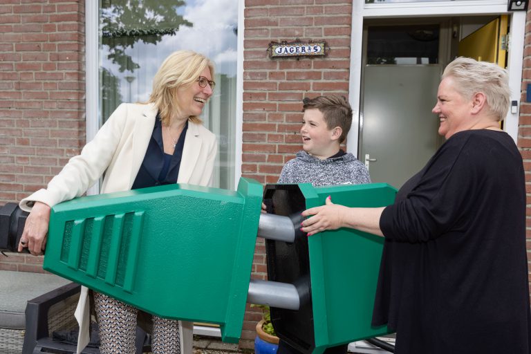 Met een symbolische groene stekker feliciteert manager Volkshuisvesting Wieke van Veldhuizen van Portaal de familie Jager uit Nijmegen met hun zojuist geplaatste zonnepanelen.